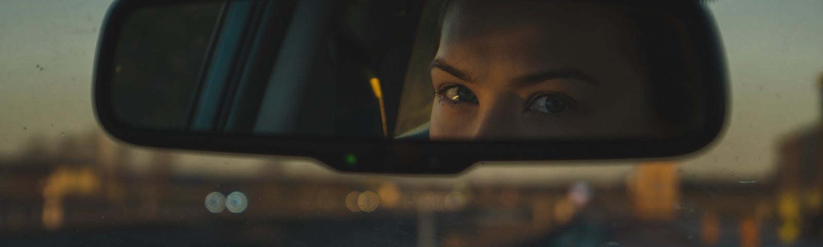 Woman looking in rear-view mirror