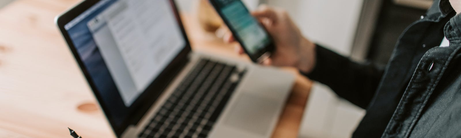 A man with a laptop and smartphone sitting at a desk