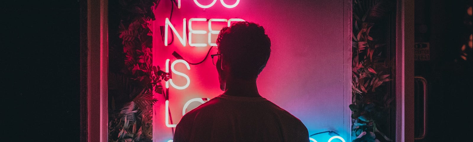 Person standing in front of neon sign.