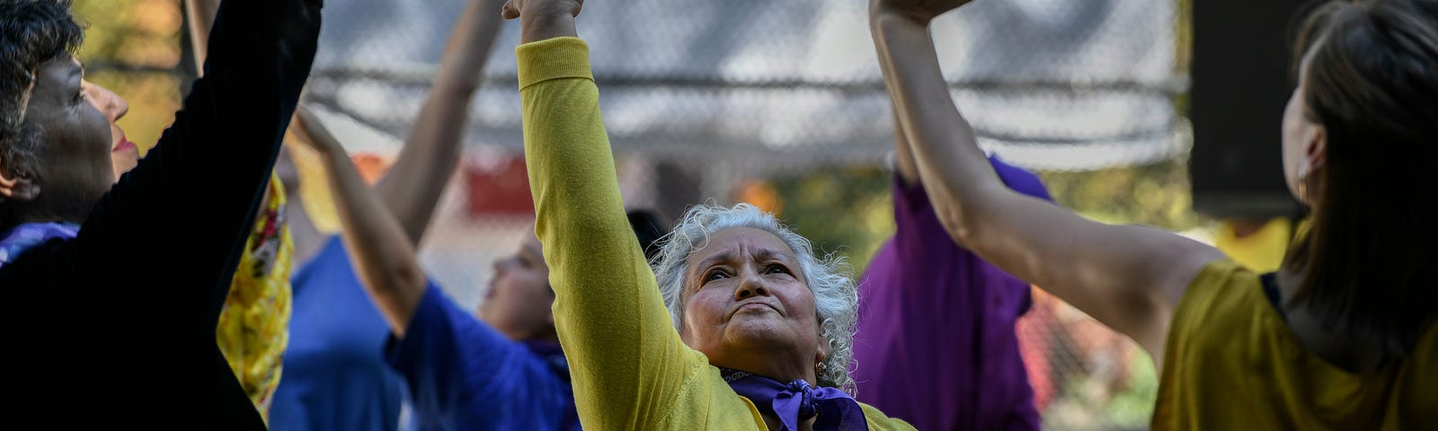 Group of performers, each reaching one hand toward the sky