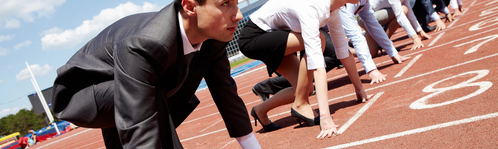 People in business suits lined up to run on a track