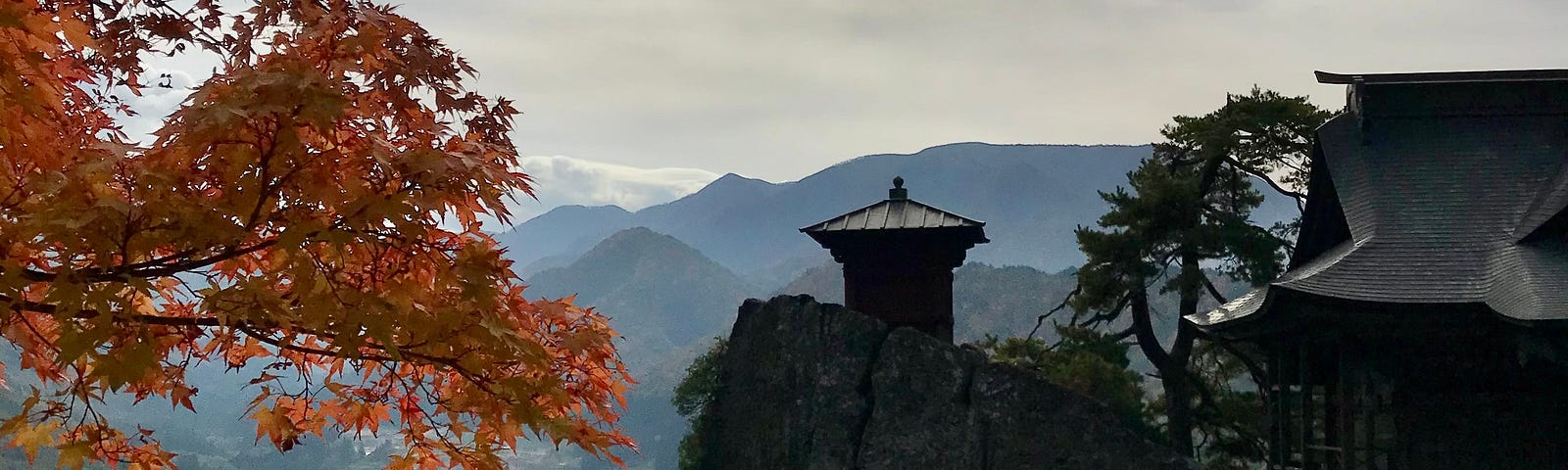 Iconic small temple on clifftop with moutains int he background