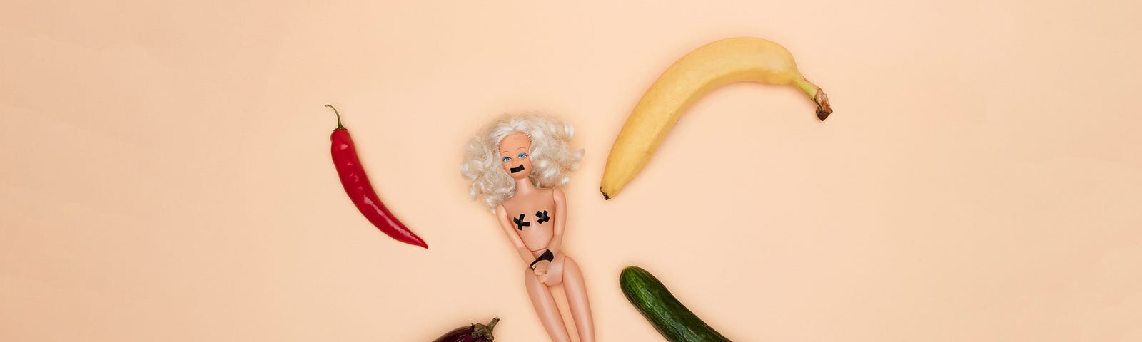 A Barbie doll surrounded by four phallic vegetables on a solid cream background