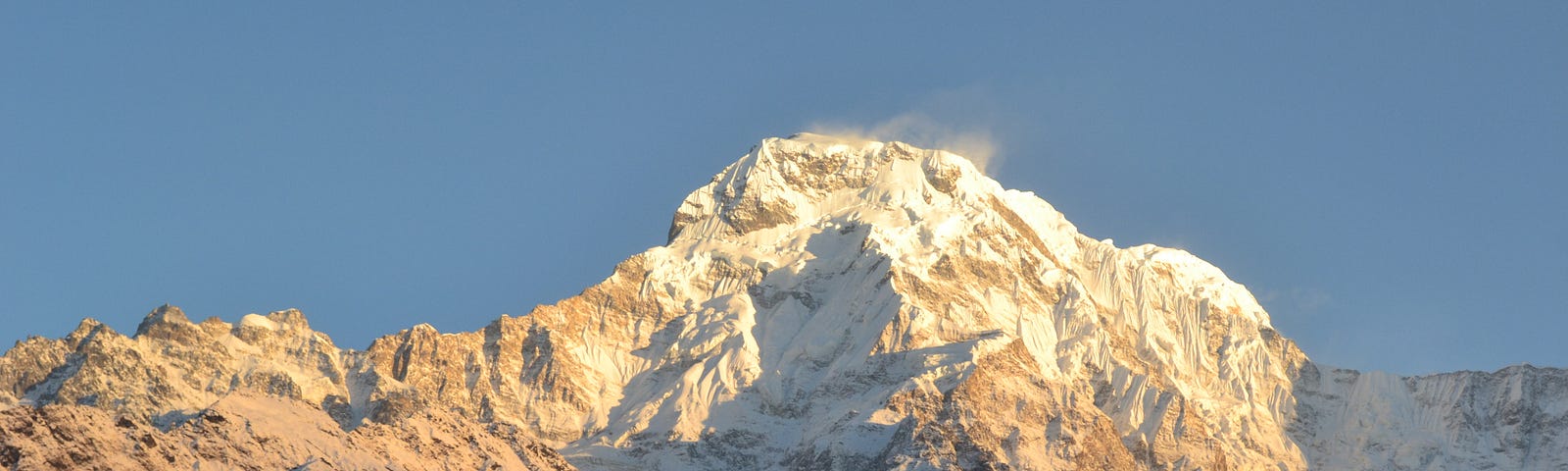 A close-up view of a snow-capped mountain with sunlight reflecting off the peak.