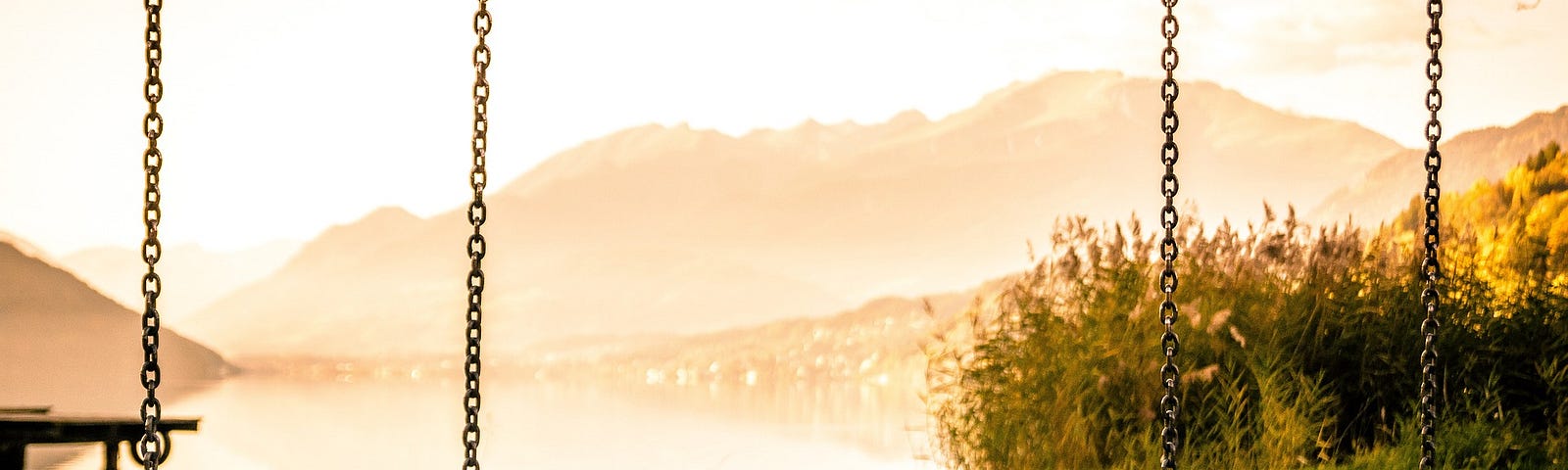 A pair of swings in a playground with mountains in the background