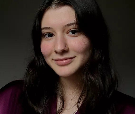 Headshot of a girl with brown hair wearing a maroon top.