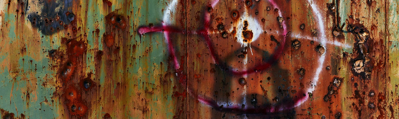 A human shadow on a multi-colored rusting steel wall pockmarked by bullet holes. Riddley Walker’s Dogs by Jim Latham