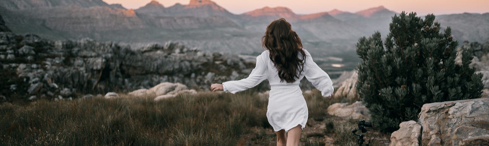 Woman with long sleeve dress running on mountainous track