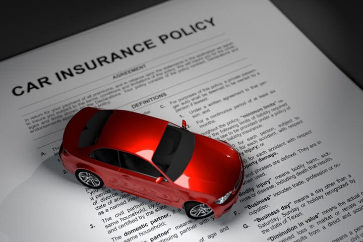 IMAGE: A red toy car on top of an insurance policy contract