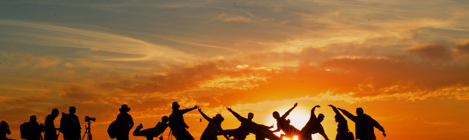 Group of people backlit by sunrise creating a human sculpture