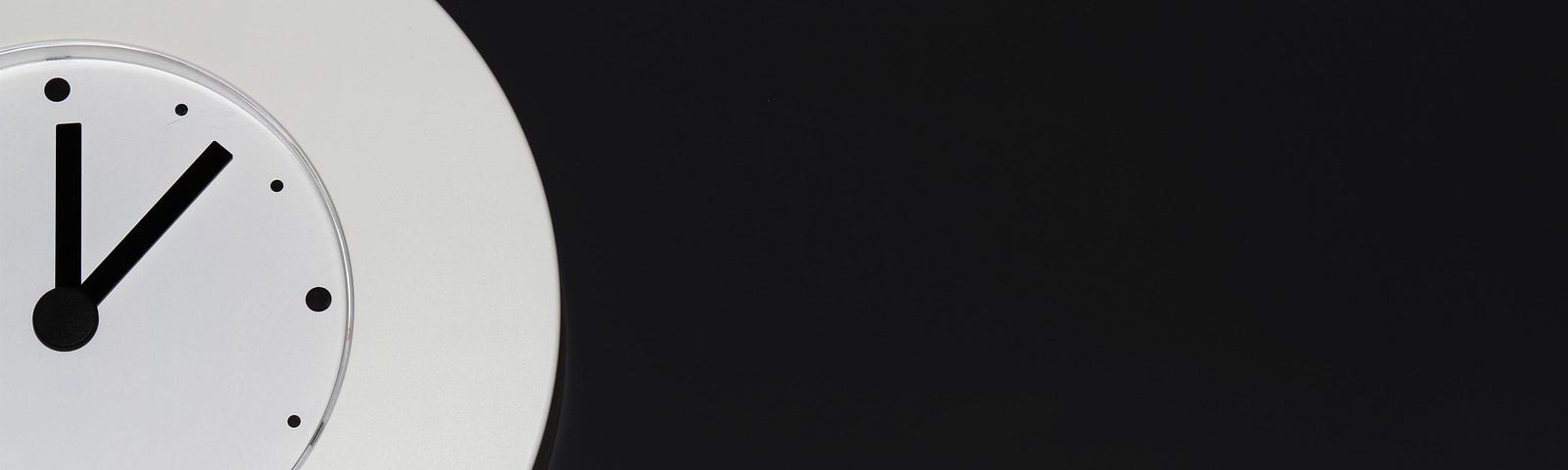 Half of a plain white round clock face with black hands on black background
