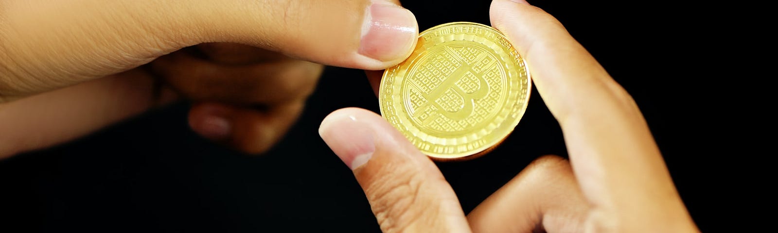 a physical bitcoin held between fingers