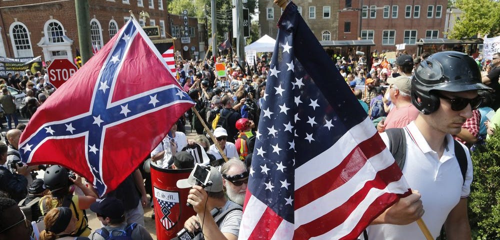 A crowd of white nationalists gather. A confederate flag and an American flag are visible.
