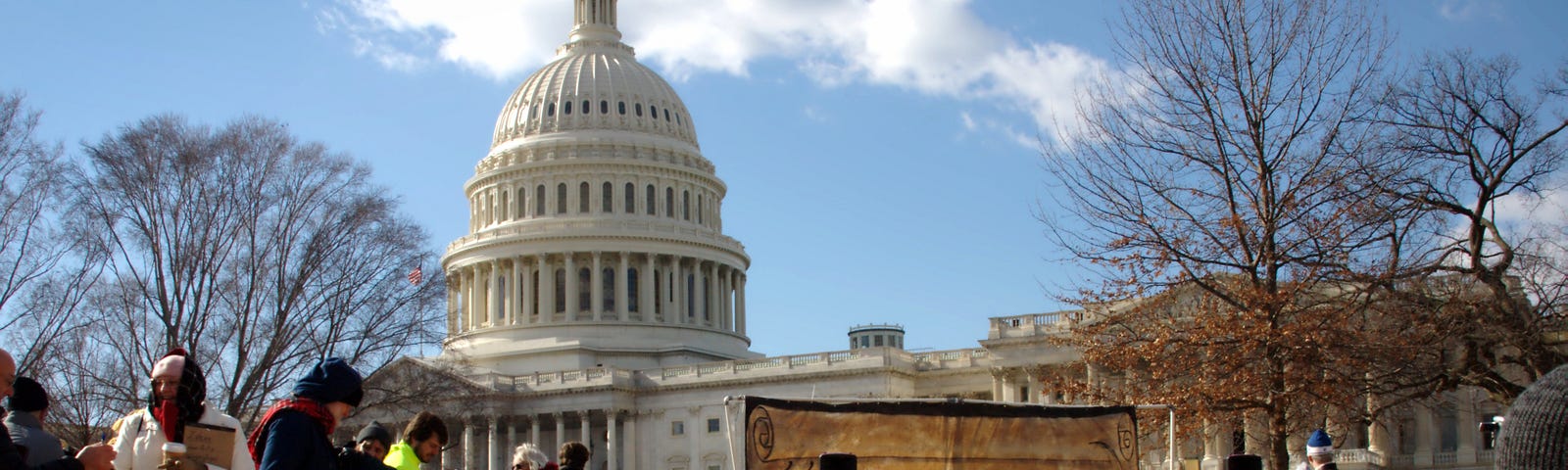 People gathered in front a large replica of the Declaration of Independence. The U.S. Capital dome looms large in the background.