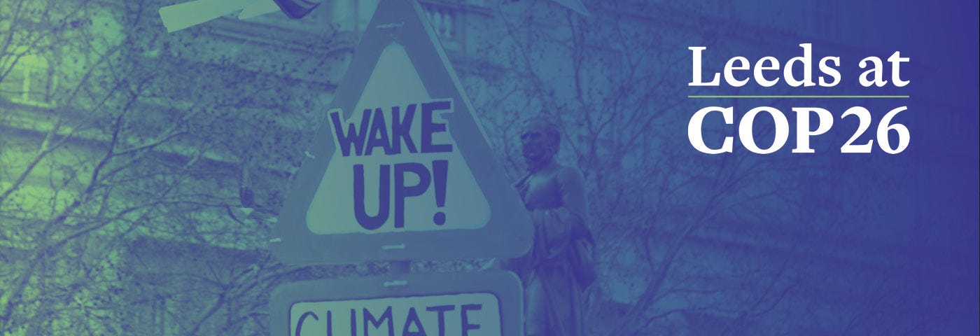 Climate protest sign saying Wake Up! Climate Emergency. Image overlaid in the corner by the text Leeds at COP26.