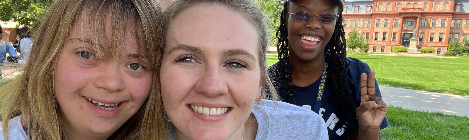 Morgan McNeil, Sophia Whitten and Grace Grubb sit together on Boettcher Commons with Main Hall in the background.