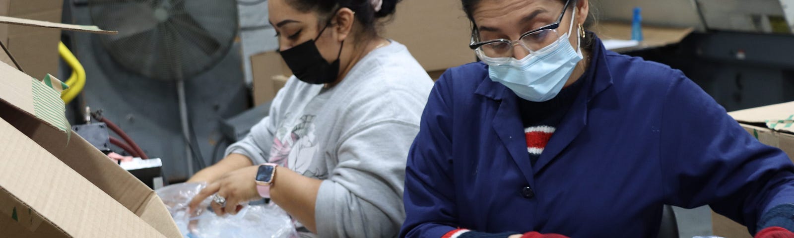 Two Latina immigrants work together to package plastic molds at a factory owned by the American Comb Corporation and Bennett Plastics. The plant is located in the industrial district of Paterson, New Jersey.