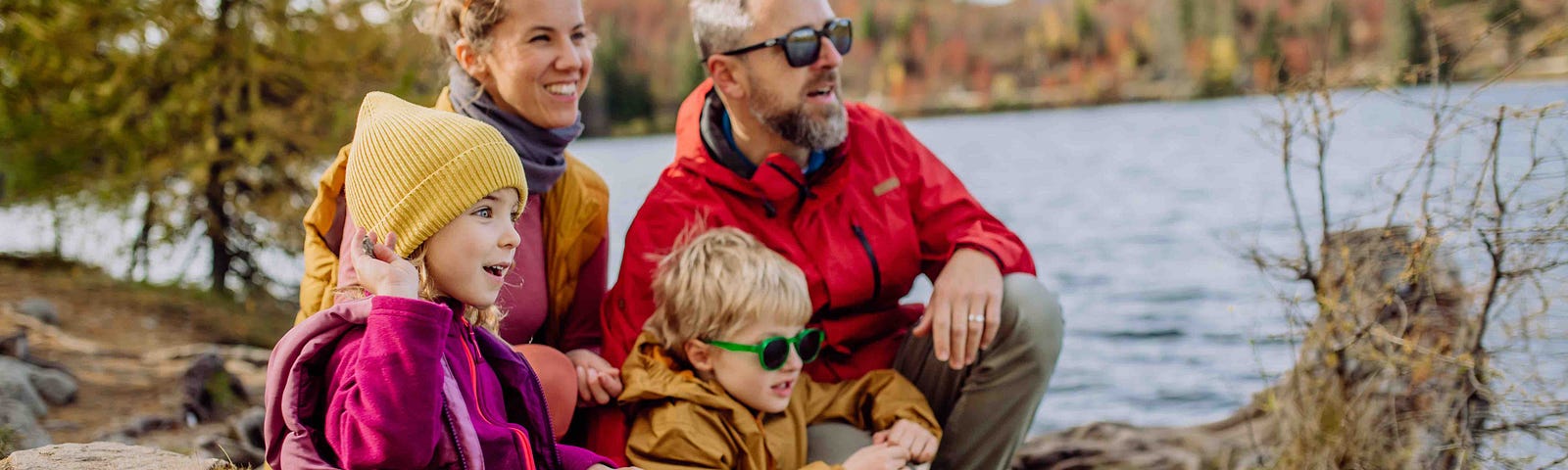 a happy family sits outside beside a lake