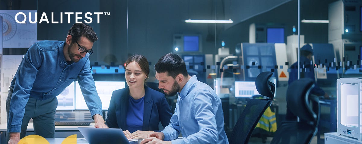 A group of people having an animated discussion around a laptop. The image has a Qualitest branding.