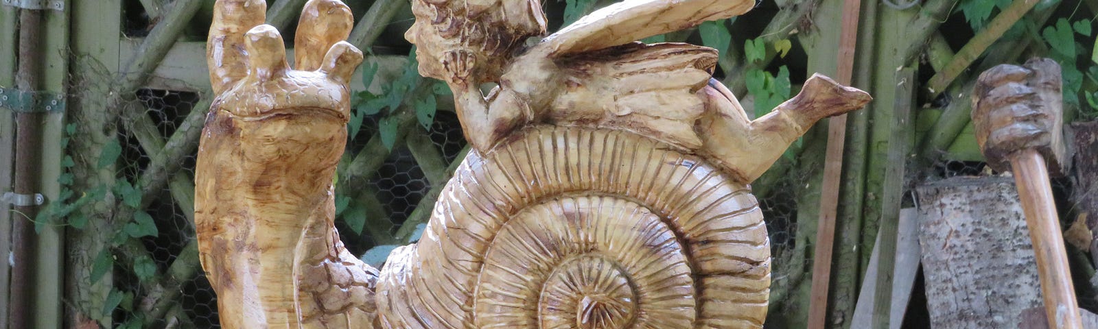 A carved wood snail and tiny fairy on its shell.