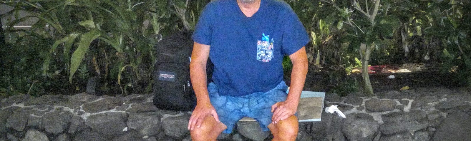 Joe sitting on a stone wall in Waikiki — Panhandling for Cannabis when I was Homeless