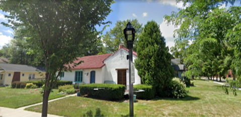 Picture of Miss Marion’s Magical Mediterranean Cottage with Spanish-style tile roof, white stucco walls, light blue trim, and Narnia-inspired light post in the front yard.