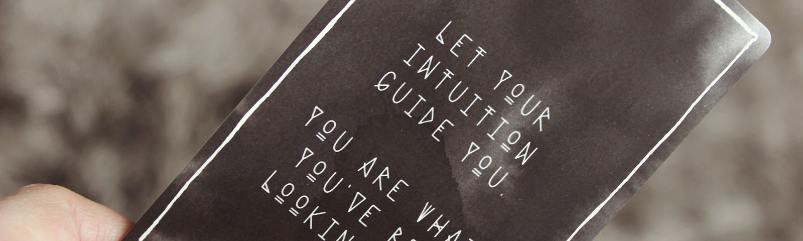 A hard hold a black card with white writing that reads, “Let your intuition guide you. You are what you’ve been looking for.”