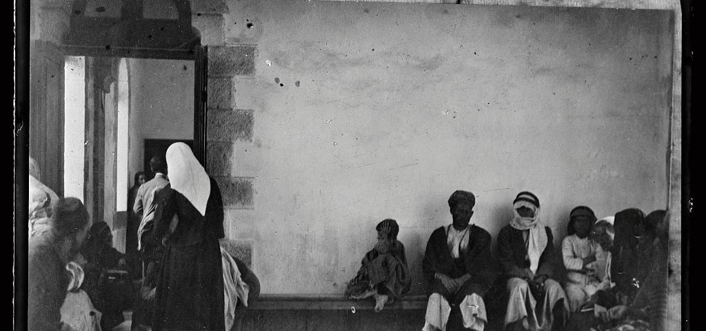 Old photo, 1918, in black and white, showing Palestine refugees in room waiting. Oppression is as old as civilisation.