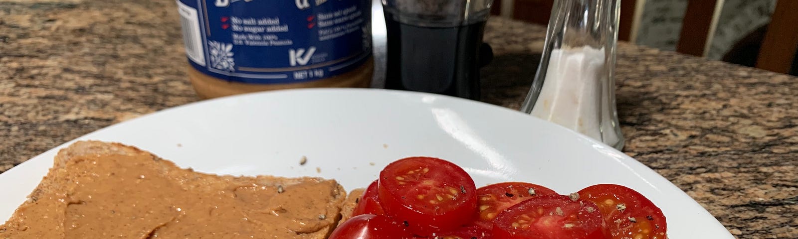 An open peanut butter tomato sandwich featuring the ingredients in the background.