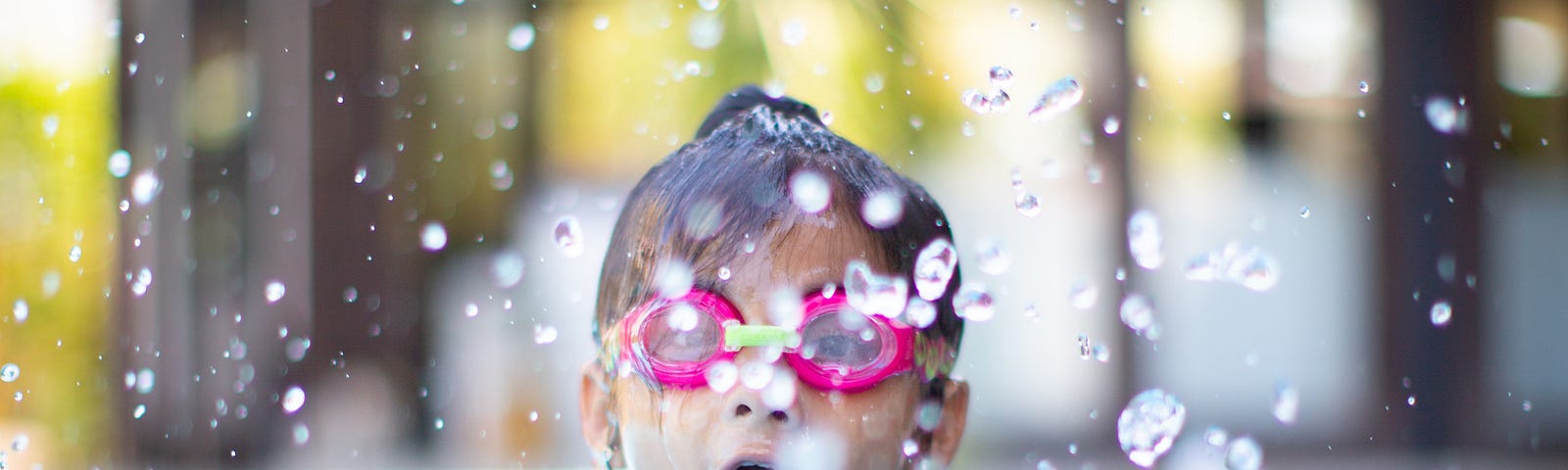 A young girl splashing in a pool.