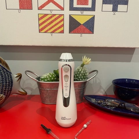 photo of a water flosser on a red bathroom counter
