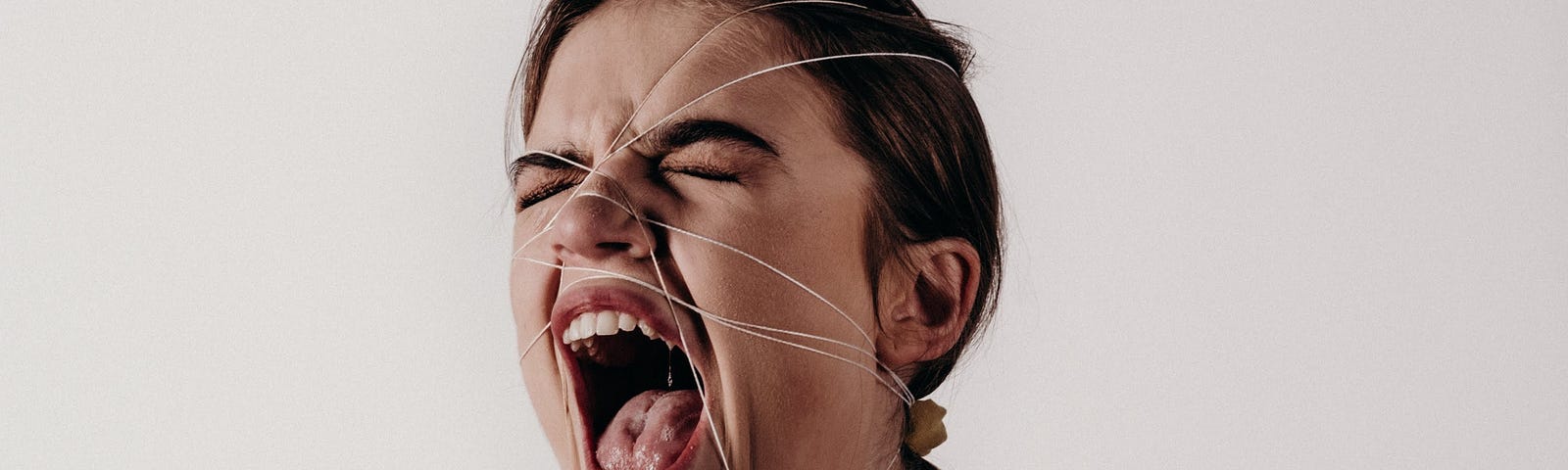 Woman screaming in anger with elastic bands binding her face