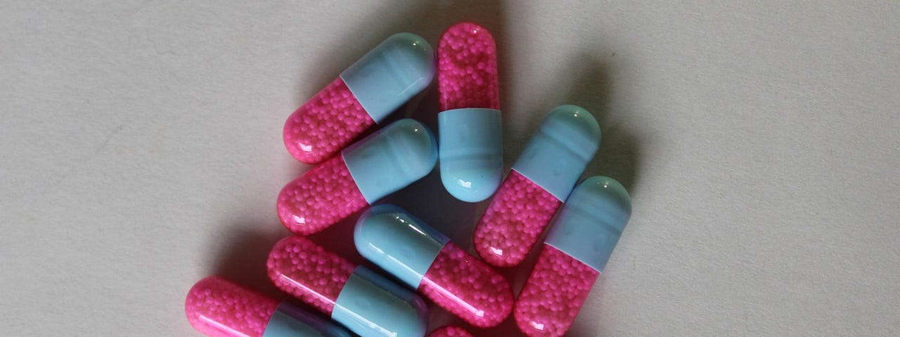 Blue and pink pill capsules in a pile.