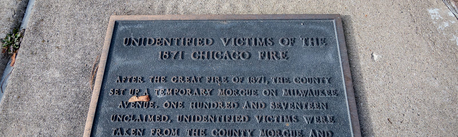 A metal plaque lays on a concrete walkway.