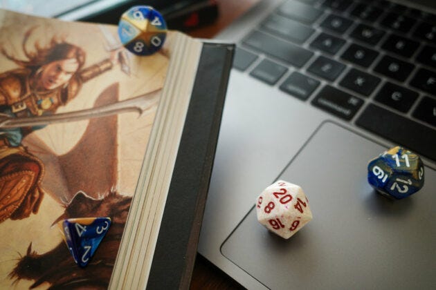 Dungeons & Dragons dice on a laptop and book.