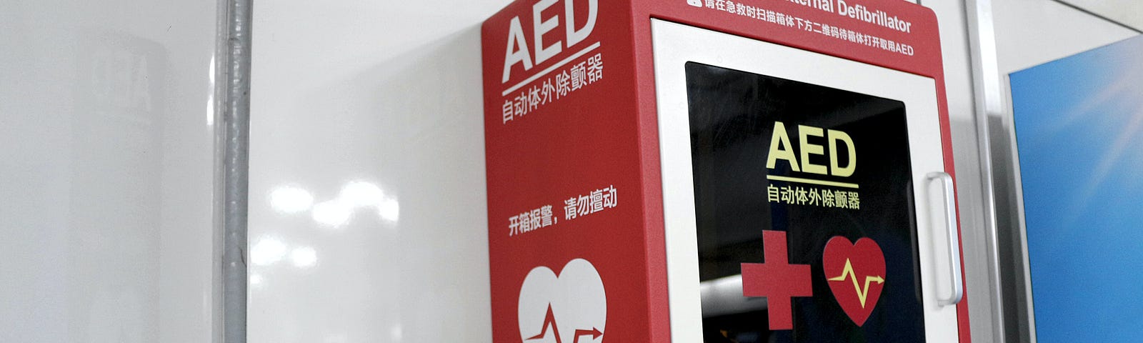 An AED (Automated External Defibrillator) in a red and white wall cabinet.