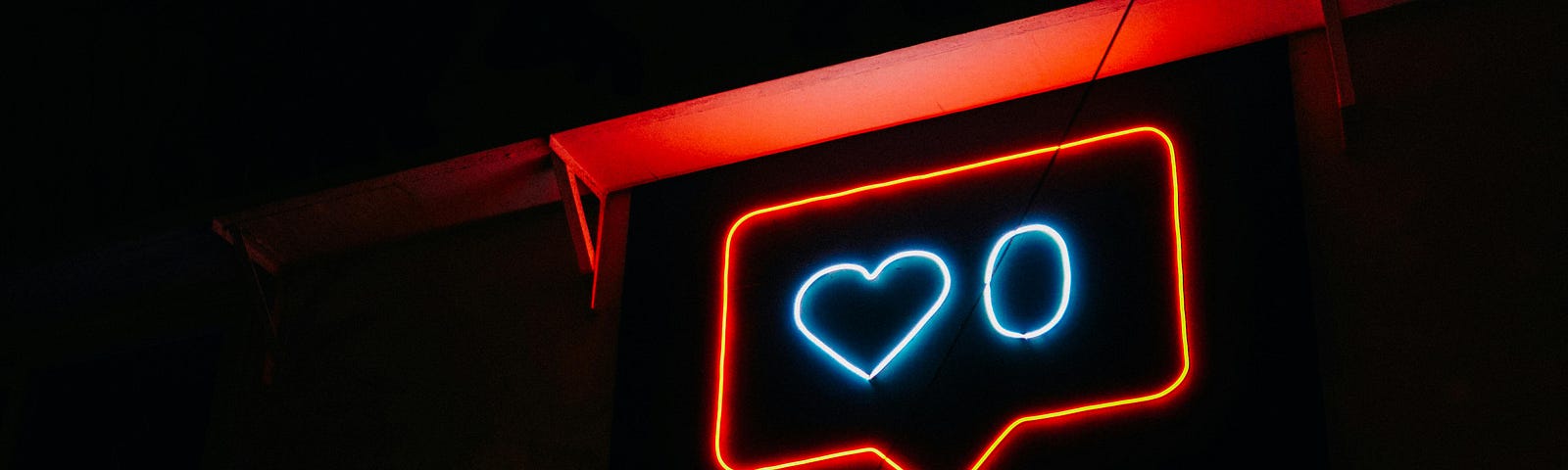 Black background. Hanging sign in the red outlined shape of an Instagram like icon with the outline of a blue heart and a 0 in the center.