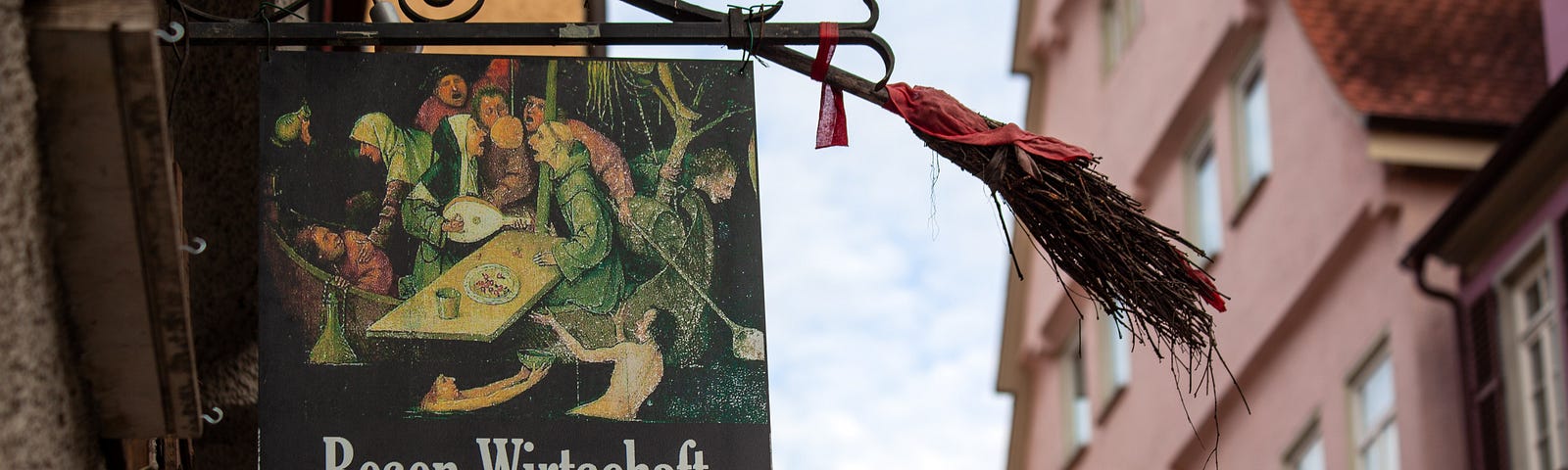 Photo of old German street, building with on wrought iron for restaurant/alehouse and a broom on top.