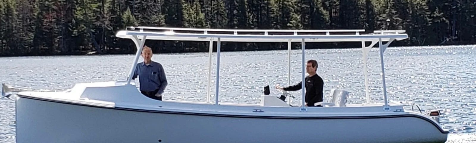 A Solar Sal 24 electric boat with two passengers on a lake.