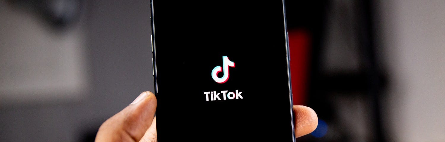 Hand holding cell phone showing TikTok logo.