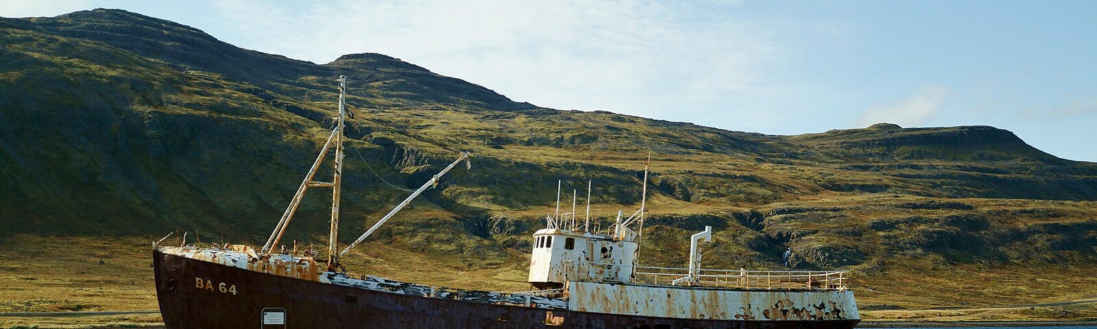 Beached boat in Iceland in front of rugged mountains.