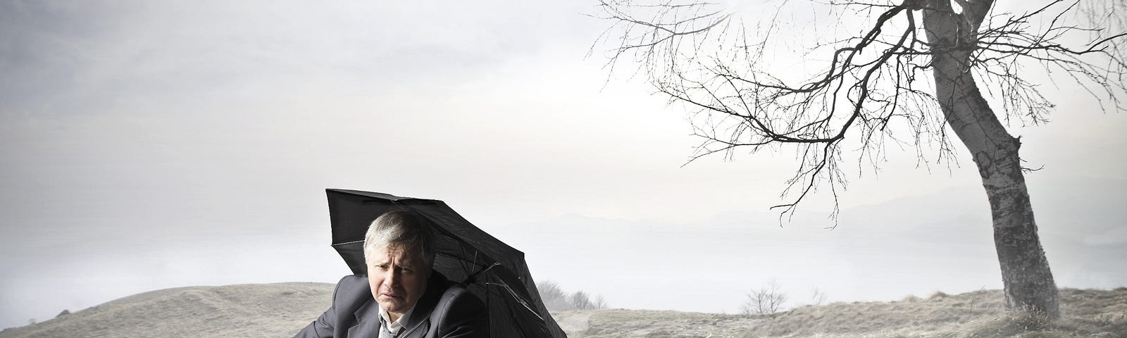 businessman sitting on the ground with umbrella