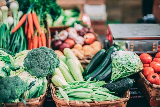 Fresh vegetables like broccoli, cucumbers, and carrots in wicker baskets.