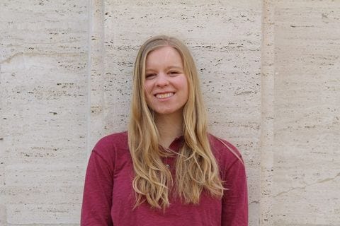 Caroline Cook wearing a pink shirt in front of a white wall.