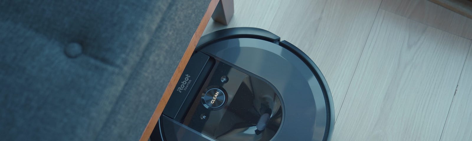 IMAGE: A Roomba robot vacuuming under a piece of furniture