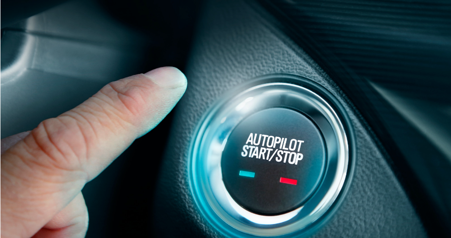 A finger hovers above a button in a car labeled “Autopilot Start/Stop.”