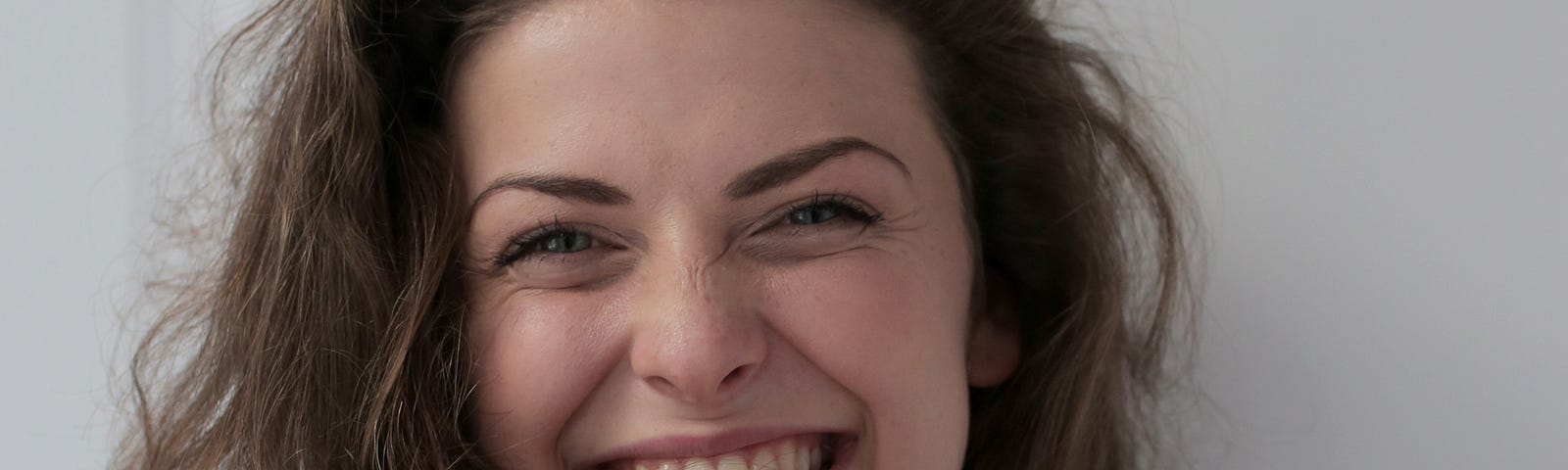 Smiling woman, playing with hair, wearing green, white checked top