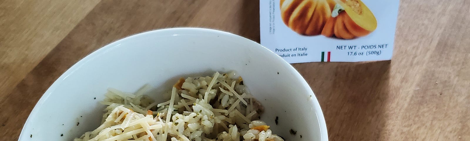 A white porcelain bowl filled with herbed risotto garnished with grated parmesan cheese