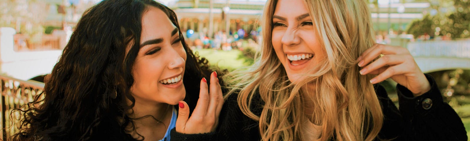 Two girls wearing dark tops smiling and laughing