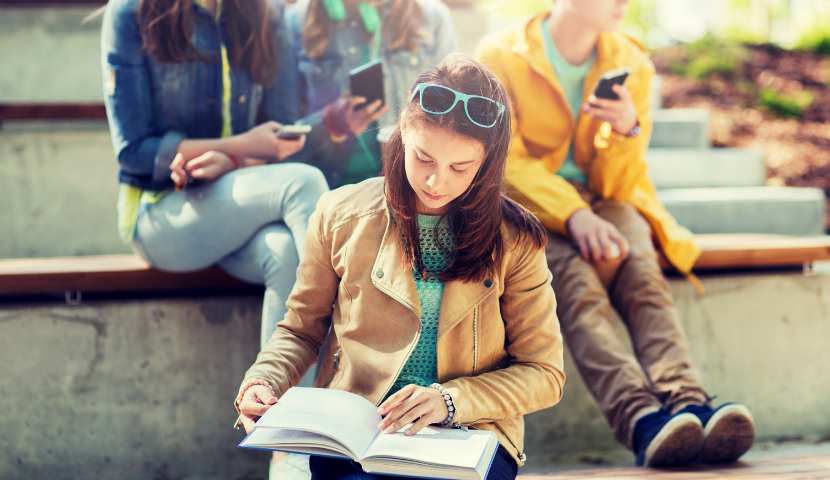 A girl reads a book outside a classroom